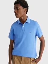 Chomba azul de Tommy Hilfiger, modelo 1985, de corte regular, con cuello tipo chomba, cartera de dos botones, logo bordado en el pecho y confeccionada en mezcla de algodón y poliéster.