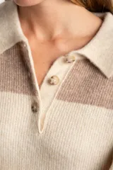 Sweater de tejido de punto grueso, color marrón y azul marino, con diseño de rayas horizontales anchas. Presenta cuello polo y abertura frontal con dos botones nacarados.