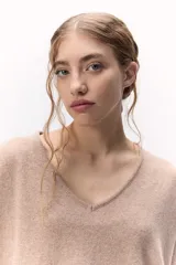 Sweater de tejido de punto color rosa pálido, con escote en V y calce holgado. Las mangas terminan en puños anchos de punto acanalado.