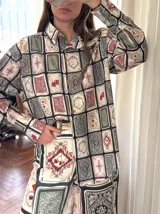 Camisa de lino con estampado de cartas de juego y dados, de corte clásico, con cuello camisero, cierre frontal con botones de madera y mangas largas.