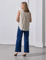 Camisa sin mangas de lino a rayas verticales azules y blancas, con cuello con solapa, escote en V, abertura central con botones y bolsillo en el pecho.