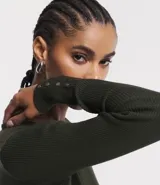 Suéter de punto color verde, con cuello barco, mangas largas y textura acanalada.