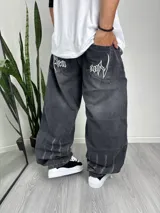Pantalón baggy de denim gris oscuro con efecto lavado. Presenta bolsillos traseros con bordados en blanco.
