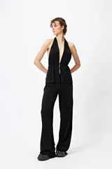 Top halter negro con escote profundo y destellos metalizados. El frunce frontal realza la silueta y el tajo sutil aporta un toque atrevido.