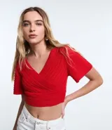 Blusa cropped roja de punto con escote cruzado en V y mangas cortas.