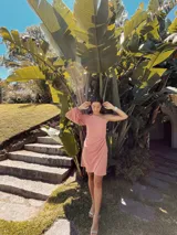 Vestido corto color rosa, con escote asimétrico de un hombro, manga larga abullonada y falda drapeada.
