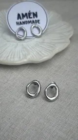 Par de aros tipo caravana de acero quirúrgico plateado, con forma irregular y diseño minimalista.