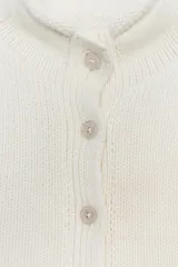 Chaqueta color blanco de tejido de punto, con cuello mao, manga corta y cierre frontal con botones.