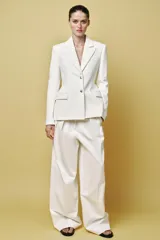 Blazer color blanco confeccionado en algodón, con cuello solapa de muescas y manga larga. Tiene bolsillos con solapa en delantero, forro interior a tono y cierre frontal con botones metálicos en relieve.