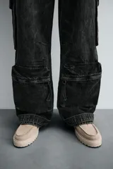 Pantalón relaxed fit de denim negro con efecto lavado, bolsillos frontales, traseros de plastrón y multifunción en perneras. Bajo ajustable con trabilla y cierre frontal con cremallera y botón.