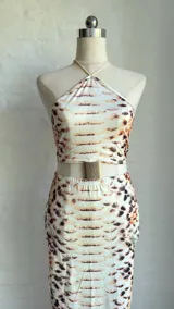 Vestido midi con estampado de piel de serpiente en tonos beige y marrón. Diseño con top halter y falda tubo con abertura lateral.
