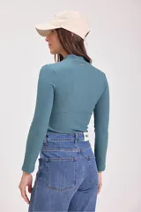 Blusa de punto canalé color verde azulado, de cuello alto y manga larga.