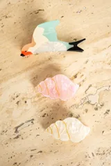 Broche con forma de colibrí con cuerpo blanco, cabeza naranja, pico negro, ala celeste y cola negra.