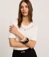 Remera blanca de viscosa con cuello redondo, mangas cortas y apliques de strass en el cuello.