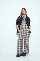 Pantalón de tiro alto, pierna amplia y caída fluida, con estampado de cuadros en tonos blanco, negro y marrón oscuro.