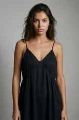 Vestido negro de tirantes finos con escote en V y corte imperio, con falda amplia y holgada.