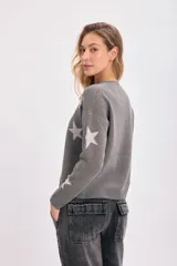 Sweater gris con estrellas blancas de punto intarsia, cuello redondo y mangas largas.