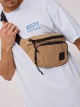 Riñonera color arena de nylon arrugado, con dos compartimentos con cierre negro y correa ajustable negra con hebilla.