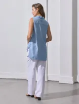 Camisa sin mangas color celeste, confeccionada en lino. Presenta cuello camisero, escote en V, abertura frontal con botones, dos bolsillos de parche en el pecho y terminación con botones en los laterales.
