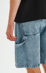 Bermuda de denim celeste con calce oversize, estilo carpintero y proceso de efecto desgaste.