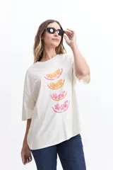 Remera blanca de corte amplio con estampado de tres rodajas de naranja y pomelo en tonos naranja y rosa.
