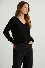 Sweater negro de manga larga con escote en V y ajuste al cuerpo.