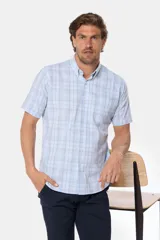 Camisa de manga corta con botones, color celeste con estampado a cuadros blancos. Hecha en Uruguay.