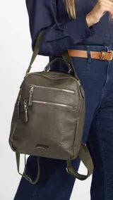 Mochila color verde oliva de símil cuero con textura. Tiene doble cierre superior, dos bolsillos frontales con cierre metálico, asa de mano rígida y correas de galón regulables.