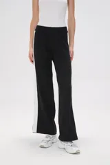 Pantalón ancho de punto color negro con una franja vertical blanca en el lateral.