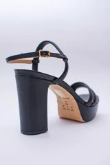 Sandalias negras de cuero con plataforma y tacón bloque alto. Tiras finas en el empeine y tobillo con hebilla dorada.