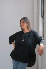 Blusa negra de corte holgado, con cuello redondo y abertura en V con botón de madera. Presenta bordados con motivos de paisley.