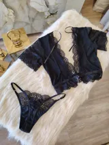 Conjunto negro de lycra, microtul y encaje suave elastizado. Incluye top con broche de gancho y espalda de microtul con detalles de encaje, y tanga regulable con forro de algodón.