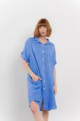 Vestido camisero corto color verde oliva, confeccionado en lino 100%. Tiene botones en la parte delantera, cuello camisero, mangas cortas con botón para arremangar y bolsillos laterales.