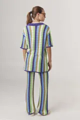 Sweater de tejido crochet a rayas verticales en tonos azul, verde, marrón y blanco, con cuello polo y cierre de botones.