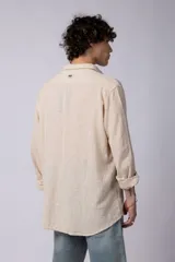 Camisa blanca de lino con cuello clásico, manga larga con puños abotonados y corte holgado. 