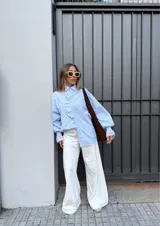 Camisa celeste a rayas verticales con cuello clásico y volados con bordado inglés en el frente y los puños.