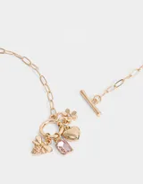 Collar dorado con cadena de eslabones y cierre de barra en forma de T. Incluye dijes colgantes: abeja, corazón, flor y cristal rosado.