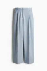 Pantalón sastrero celeste de corte holgado con tiro alto y cierre con corchete y botón ocultos. Piernas amplias con pinzas, pliegues adelante y atrás, bolsillos al bies y bolsillos decorativos atrás.