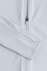 Campera deportiva corta celeste con cuello alto, cierre frontal, mangas largas con orificios para los pulgares y tecnología SoftMove™ y DryMove™.