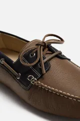 Mocasín casual color marrón fabricado en cuero con acabado serraje, horma redonda, detalle de lazo en el empeine y suela de goma.