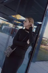 Vestido negro de largo midi, confeccionado en tejido grueso con efecto ante. Presenta mangas largas, escote con abertura en el pecho, cintura elastizada con frunces, tajo lateral y cuello medio alto.