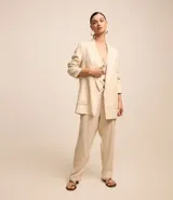 Blazer largo color beige confeccionado en viscosa y lino, con cuello solapa, bolsillos y forro estampado a rayas.