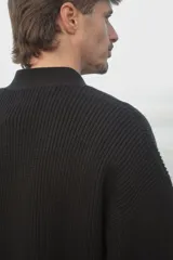 Cardigan negro de punto con cuello en V, cierre frontal con botones y corte clásico.