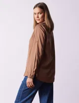 Camisa marrón de lyocell, marca Dash. Cuello con solapa y abertura central con botones. Largo de manga regulable con presilla y botón. Delantera con bolsillos aplicados.