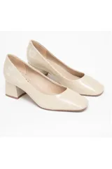 Zapato de salón color beige con textura de piel de cocodrilo, tacón cuadrado y puntera ligeramente cuadrada y redondeada.