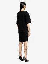 Vestido blanco de manga corta, estilo camiseta, confeccionado en jersey de algodón orgánico. Presenta un lazo frontal ajustable que genera un efecto drapeado y un recorte bordado en el frente.