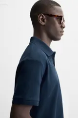 Polo azul marino de punto con textura acanalada vertical, corte regular fit, cuello solapa con abertura frontal y mangas cortas.