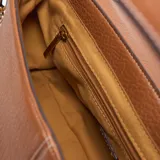 Bandolera de PU color habano con textura granulada, diseño de solapa curva y herrajes dorados. Incluye una correa ancha de tela estampada en tonos beige y marrón, y una correa larga regulable y desmontable.