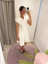 Vestido midi blanco con escote en V, abotonado al frente, mangas cortas con volados y falda evasé.