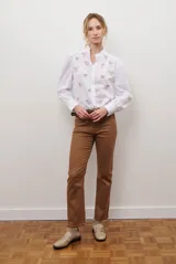 Camisa azul marino con estampado floral en color lila, cuello mao con volantes, cierre frontal de botones y mangas largas abullonadas con puños elásticos.